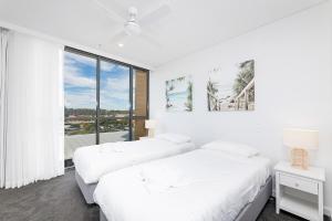 two beds in a white room with a window at Serenity at Solaris 101 in Forster