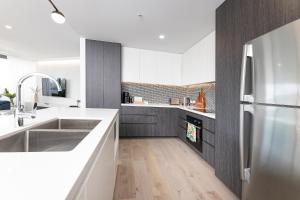 a kitchen with a stainless steel refrigerator and wooden floors at Serenity at Solaris 101 in Forster