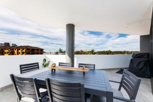 a table with chairs and a bench on a balcony at Serenity at Solaris 101 in Forster