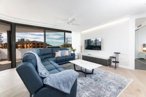 a living room with a blue couch and a table at Serenity at Solaris 101 in Forster