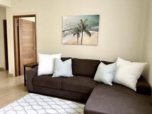a living room with a brown couch and palm trees at Tumon Isa 16 Condo in Tamuning