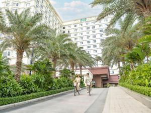 岘港DLG岘港酒店的两个人骑着自行车沿着酒店前的人行道行驶。 更多206张照片