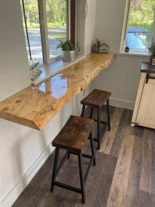 a kitchen with a wooden counter with two stools at Palmers Cozy Cottage mountainside getaway in Sutton +20 photos