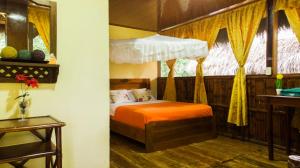 Caiman Eco Lodge في Aguarico: غرفة نوم بسرير ولحاف برتقالي