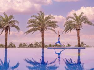 a woman is doing yoga on a trampoline next to palm trees at DLG Hotel Danang in Danang