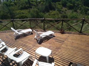 un grupo de sillas blancas en una terraza de madera en Cabañas la bonita en Trapiche