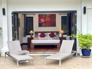 Un dormitorio con una cama y dos sillas. en Villa Suksan - Kubu, en Nai Harn Beach 26 fotos más