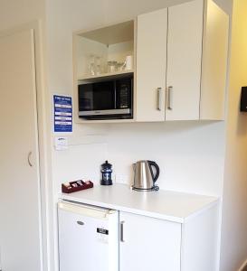 a kitchen with a microwave and a refrigerator at Panorama Motor Lodge in Timaru