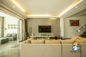 sala de estar con sofá y TV en Villa Black Pearl - by Unicorn Villas Bali en Padangbai