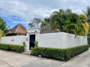 Una valla blanca delante de una casa con palmeras. en Villa Suksan - Kubu, en Nai Harn Beach