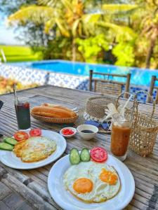 een houten tafel met 2 borden ontbijtproducten en drankjes bij The Ruong Resort in Vung Tau