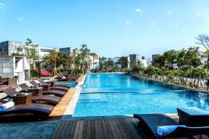 a swimming pool with chaise lounge chairs on a building at Jeju Breeze in Seogwipo
