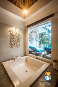 Villa Black Pearl - by Unicorn Villas Bali في بادانجباى: حوض استحمام كبير في غرفة مع نافذة