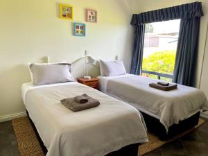 two beds in a room with a window at House of the Young - Emu Bay in Emu Bay