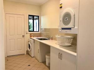 a kitchen with a sink and a washing machine at House of the Young - Emu Bay in Emu Bay