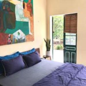 1 dormitorio con 1 cama y una pintura en la pared en Giang House en Hòa Bình