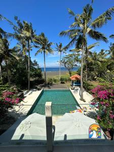 een zwembad met uitzicht op de oceaan en palmbomen bij Villa Black Pearl - by Unicorn Villas Bali in Padangbai