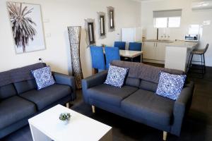 a living room with two couches and a kitchen at Zorba Waterfront Motel in Batemans Bay