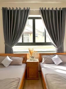 a bedroom with two beds and a window with curtains at Khoảng Lặng ATP in Da Lat