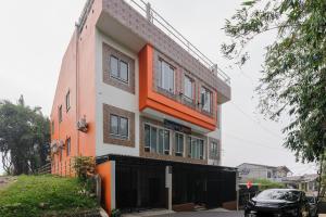 an orange and white building with a car parked in front of it at RedDoorz near The Jungle Waterpark Bogor in Bogor
