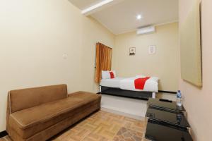 ein Wohnzimmer mit einer Couch und einem Bett in der Unterkunft RedDoorz near The Jungle Waterpark Bogor in Bogor