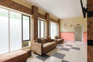 a living room with two couches and windows at RedDoorz near The Jungle Waterpark Bogor in Bogor