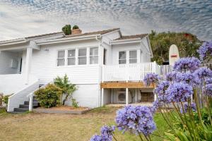 a white house with purple flowers in front of it at Barkly Beach House Warrnambool in Warrnambool