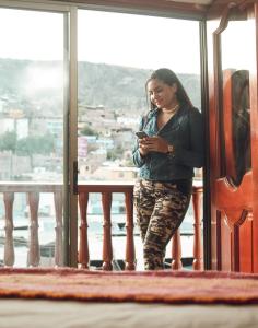 Una donna in piedi su un balcone che guarda il suo cellulare di Altipacha Ayacucho Hotel ad Ayacucho