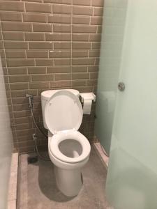 a bathroom with a white toilet and a brick wall at PassGo Digital Airport Terminal 2 Soekarno Hatta in Rawabagol