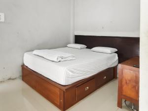 ein Bett mit weißer Bettwäsche und einem Holzrahmen in der Unterkunft RedDoorz Syariah near Terminal Terpadu Langsa in Birimpontong