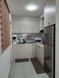 cocina con armarios blancos y nevera de acero inoxidable en The Quartz 3 Bedroom Apartment with fully furnish and fully aircond, infinity pool, Corner lot with seaview and city view centre of malacca city en Tranquerah