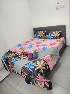 a bed with a colorful comforter and shoes on it at The Quartz 3 Bedroom Apartment with fully furnish and fully aircond, infinity pool, Corner lot with seaview and city view centre of malacca city in Tranquerah