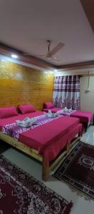 a bedroom with a large bed with pink sheets at ALEGRO HOLIDAY HOMES in Palolem