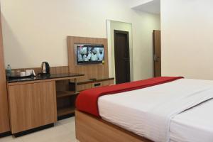 a bedroom with a bed and a desk with a television at HOTEL PRITAM PARK in Jālgaon