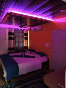 Habitación con cama con luces moradas. en ALEGRO HOLIDAY HOMES, en Palolem