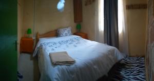 a bedroom with a bed with a white blanket and a window at Rhino hillside in Sekenani