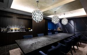 a dining room with a black table and chandeliers at Cross Hotel Osaka in Osaka