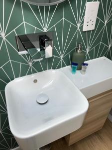 a white sink in a bathroom with a green wall at Central ensuite guest unit with free parking in Brighton & Hove