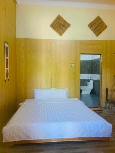 a bedroom with a white bed with a wooden wall at Green Homestay Mai Chau in Mai Châu