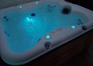 une baignoire blanche remplie d'eau bleue dans l'établissement River Cottage Brecon: Hot Tub, Fire, Balcony, Wifi, à Brecon 23 autres photos