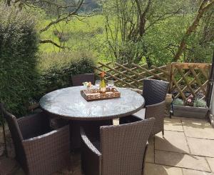 a table with chairs and a bottle of wine on it at River Cottage Brecon: Hot Tub, Fire, Balcony, Wifi in Brecon