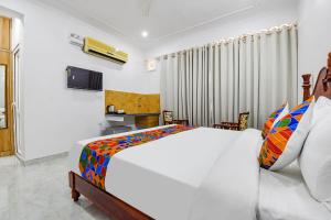 1 dormitorio con 1 cama blanca grande con almohadas coloridas en FabHotel Umrao Haveli with Pool, en Jaipur