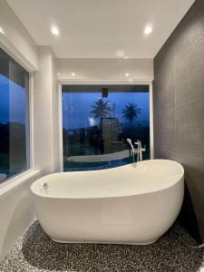 uma banheira branca na casa de banho com uma janela em Puerto Galera Seascape by Aussie Staycation em Puerto Galera