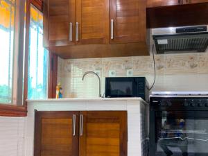 a kitchen with wooden cabinets and a microwave and a stove at Appartement chic in Pointe-Noire