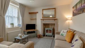 a living room with a couch and a fireplace at Herbal Cottage in Eyam