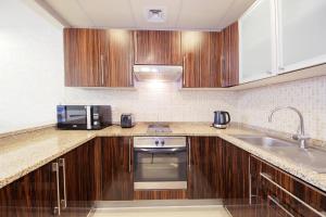 a kitchen with wooden cabinets and a sink at SHH - Furnished 1BR Apartment in Goldcrest Executive, Jumeirah Lake Towers in Dubai