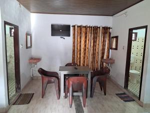 una sala da pranzo con tavolo, sedie e TV di Mountain View cottage Mankulam a Munnar