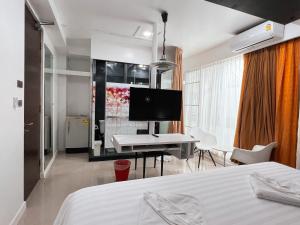 a bedroom with a bed and a desk and a tv at The Color Kata in Kata Beach
