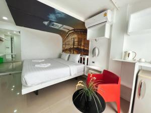 a small bedroom with a white bed and a red chair at The Color Kata in Kata Beach