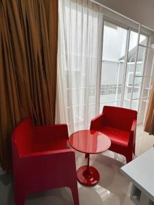 a living room with two red chairs and a table at The Color Kata in Kata Beach